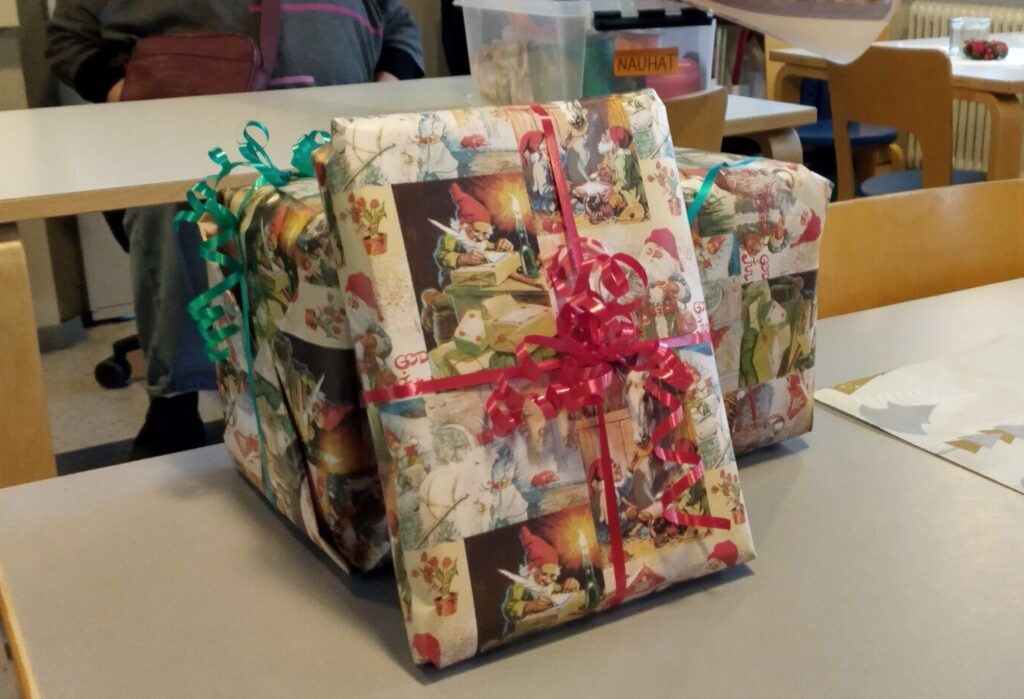 Lahjapaketit, jotka on kääritty joulukuosiin koristeltuun paperiin ja sidottu värikkäillä nauhoilla.